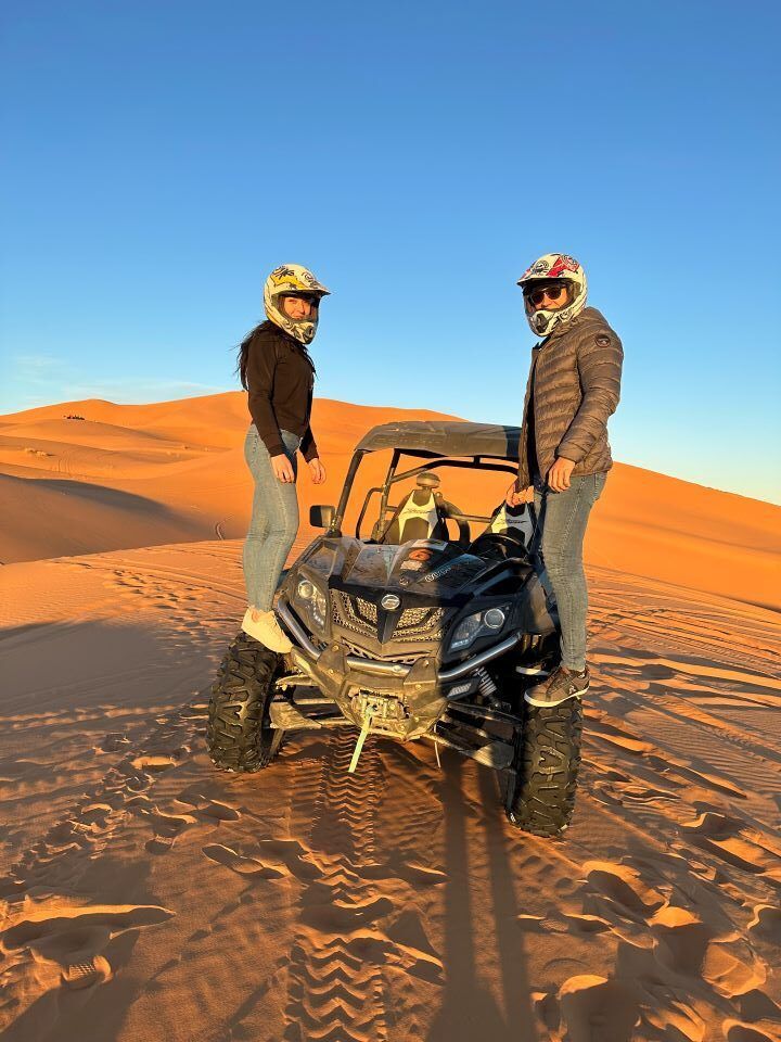buggy desierto con pareja en los laterales del buggy con casco en la cabeza en marruecos